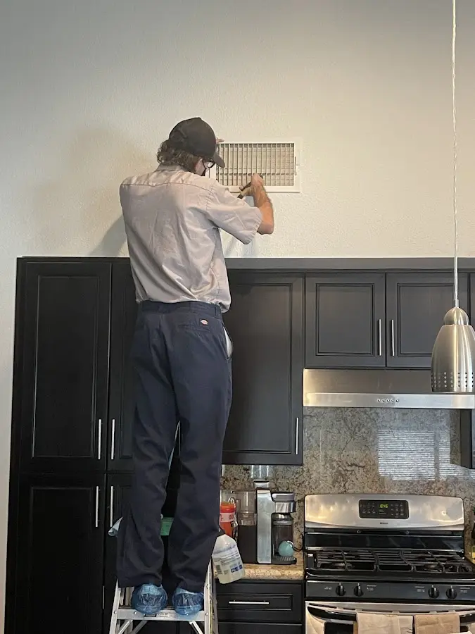 Technician inspecting an air vent during HVAC service in El Rio